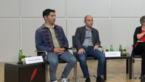Alexander Warzilek (links) bei einer Podiumsdiskussion des Netzwerk Klimajournalismus. Das Bild ist in schwarz-weiß gehalten.