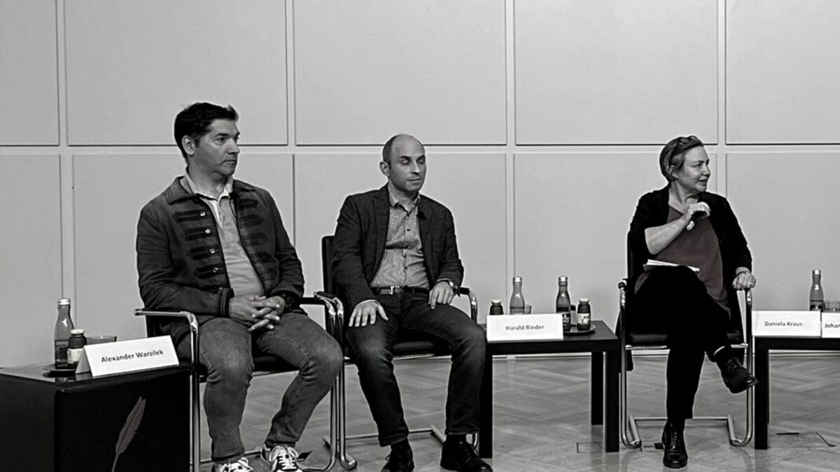 Alexander Warzilek (links) bei einer Podiumsdiskussion des Netzwerk Klimajournalismus. Das Bild ist in schwarz-weiß gehalten.
