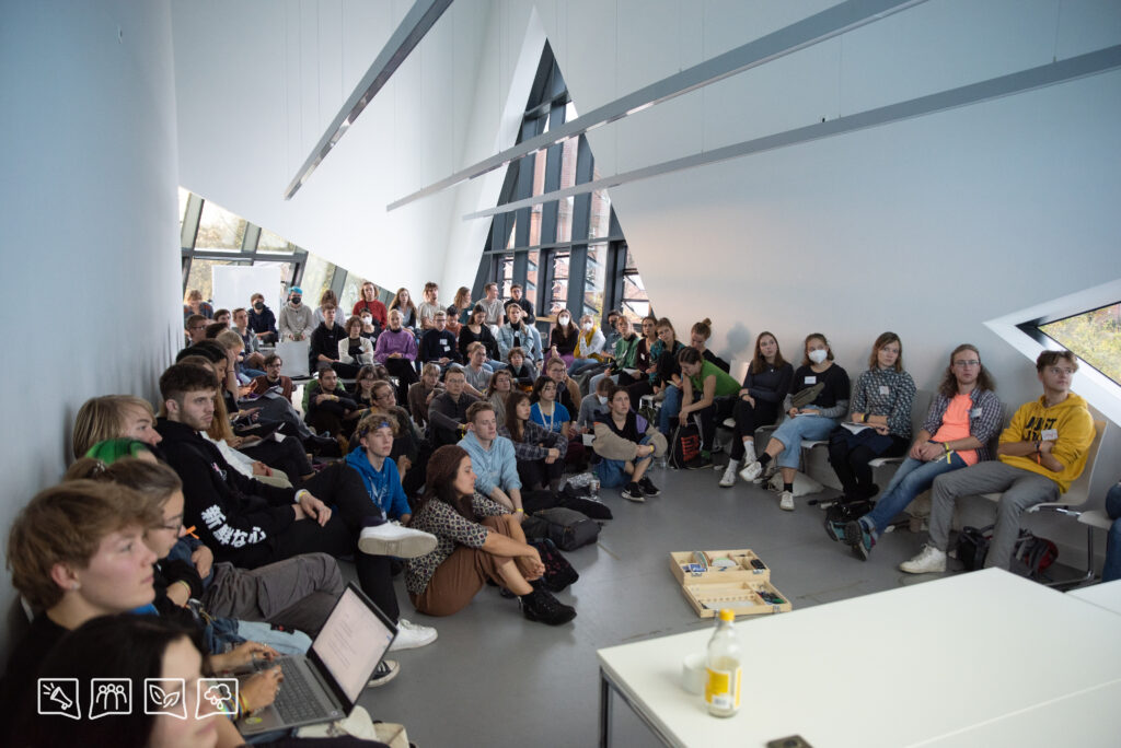 Rund 50 junge Leute sitzen in einem Raum bei der LCOY Deutschland 2022 und hören bei einem Klimajournalismus-Workshop zu.